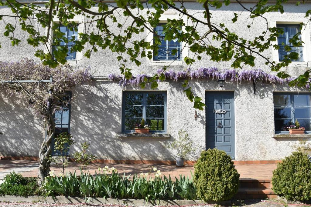 Ray-sur-Saône乐提耶德赫住宿加早餐旅馆的白色房子外墙上紫色紫色的紫藤