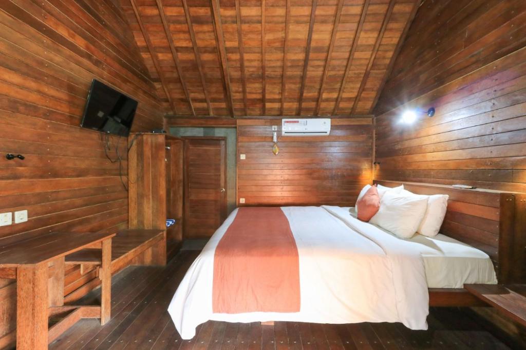 珀尼达岛Waterside inn Nusa Penida的木制客房内的一间卧室,配有一张床
