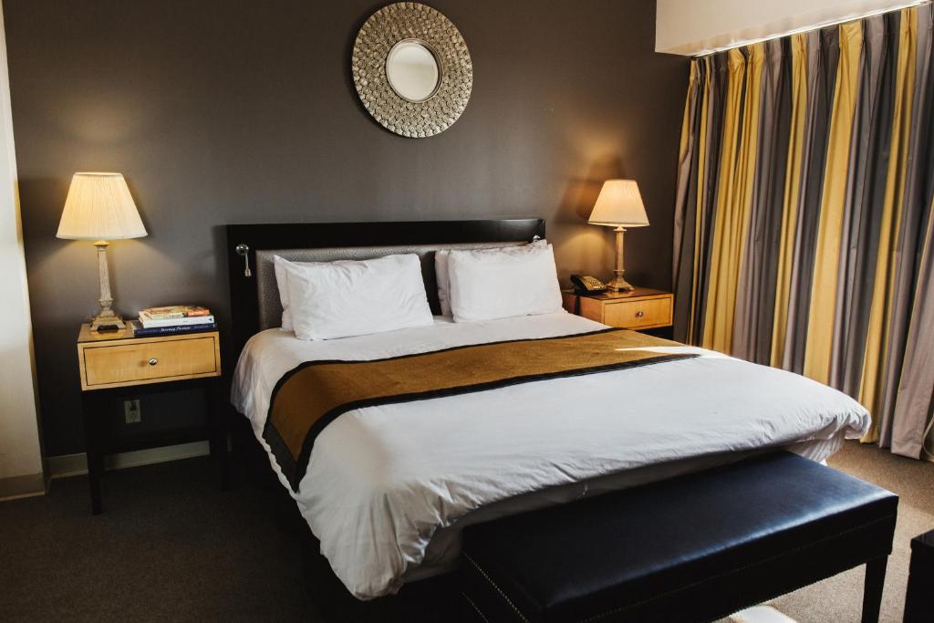 斯坦福德斯坦福德套房酒店的一张位于酒店客房的床位,配有两盏灯和一面镜子