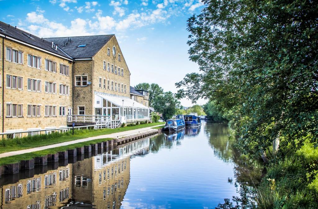 斯基普顿Hotel Rendezvous - Skipton - N Yorkshire的城市的运河,有建筑物和船只