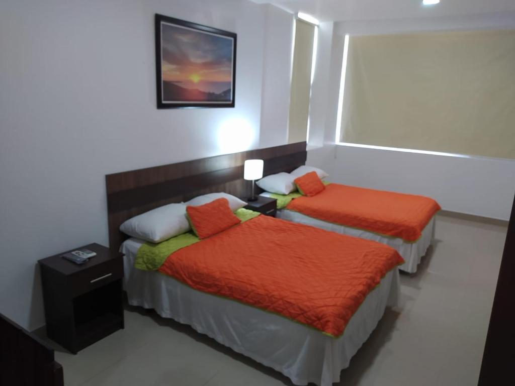 曼塔Manta Airport Hotel的客房配有2张带橙色棉被的床。
