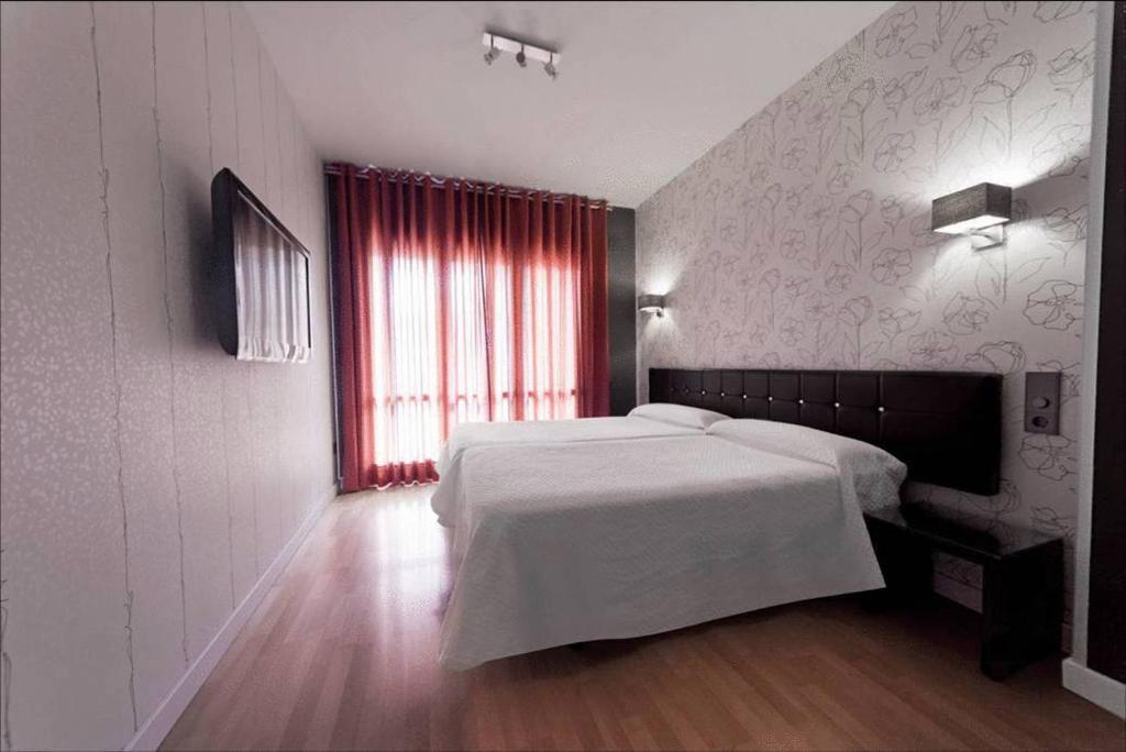 韦斯卡Hospedium Hostal Un Punto Chic的卧室配有白色的床和红色窗户。