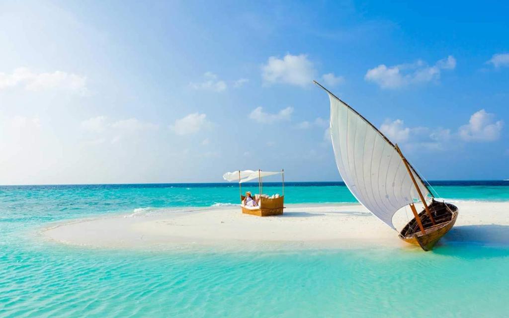古莉Pearlshine Retreat Maldives的海滩上一艘带白色遮阳伞的船