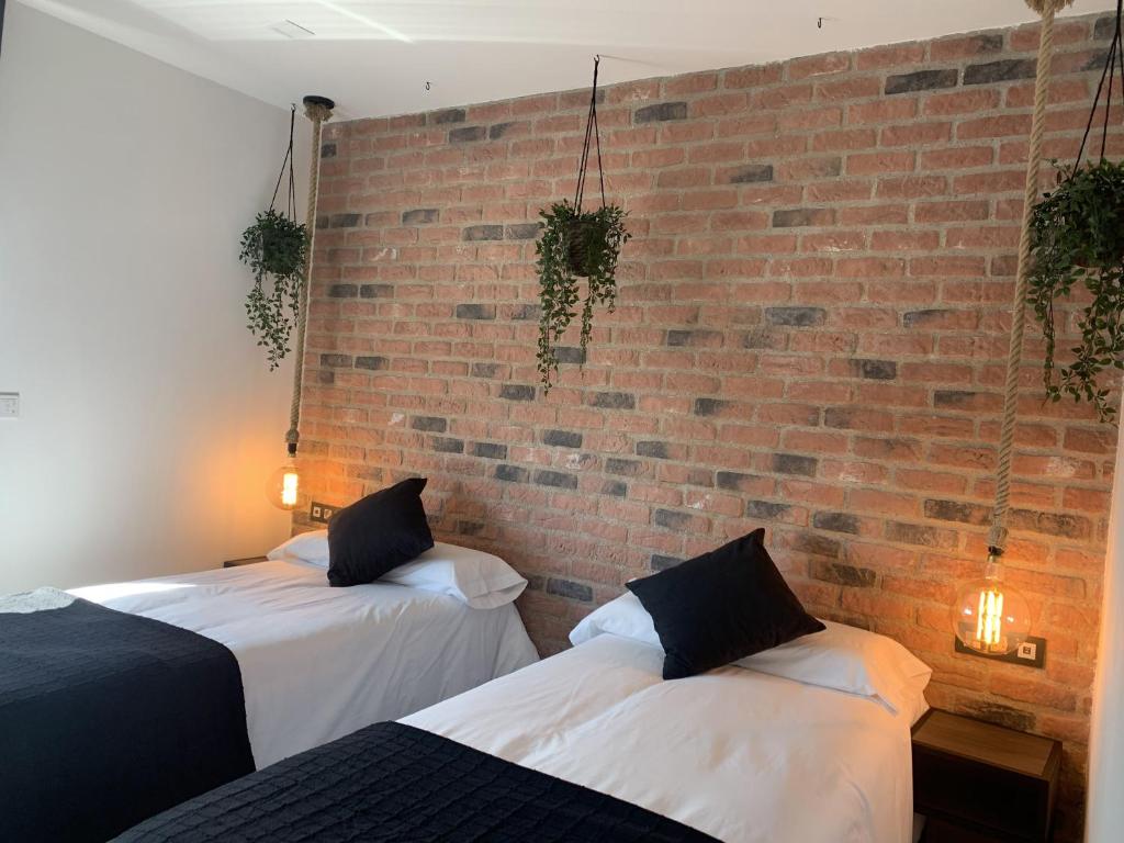 乌马内斯-德马德里Hotel Riojano的砖墙客房的两张床
