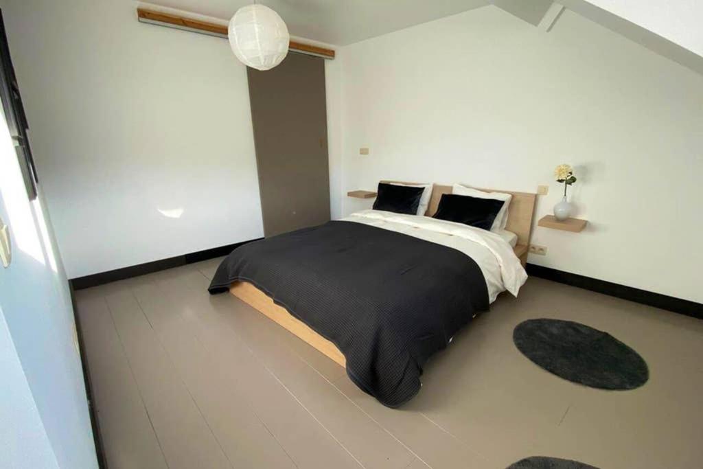 迪南À deux PATENIER de Dinant的卧室配有一张大床,提供黑色床单和枕头。