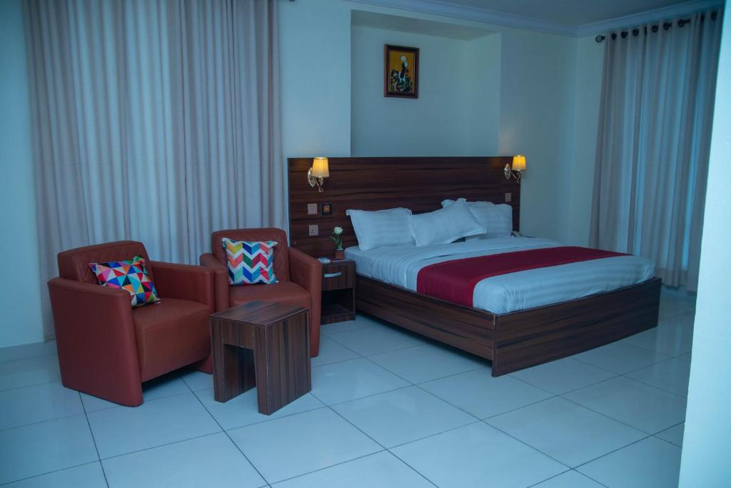 拉各斯Posh Hotel and Suites Victoria Island的配有一张床和一把椅子的酒店客房