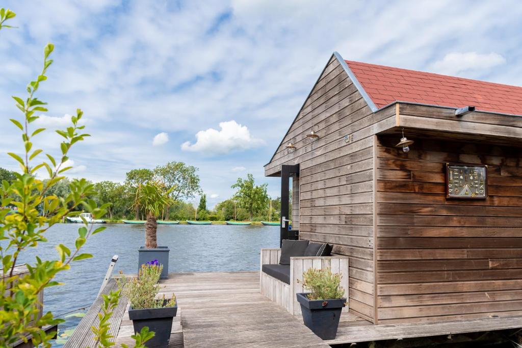 莱茵河畔阿尔芬Aangenaam op de Rijn, woonboot, inclusief privé sauna的水面上码头上的木屋