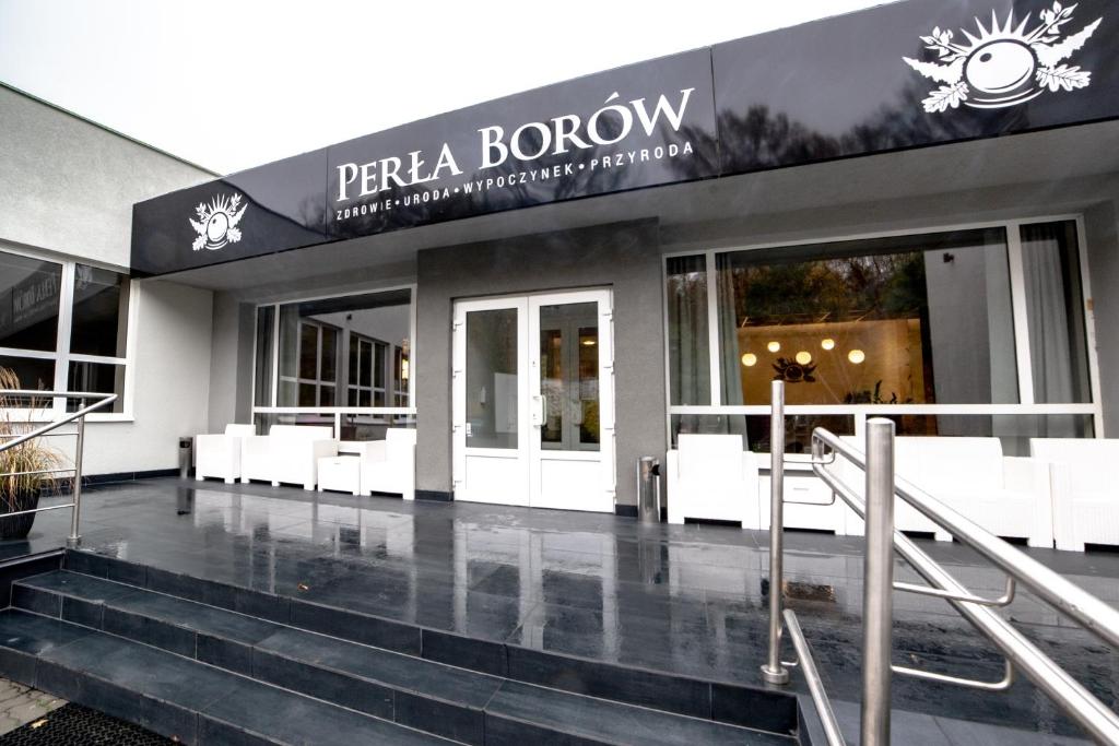 特伦Ośrodek Wypoczynkowo-Rehabilitacyjny Perła Borów的大楼前方有白色长凳的商店