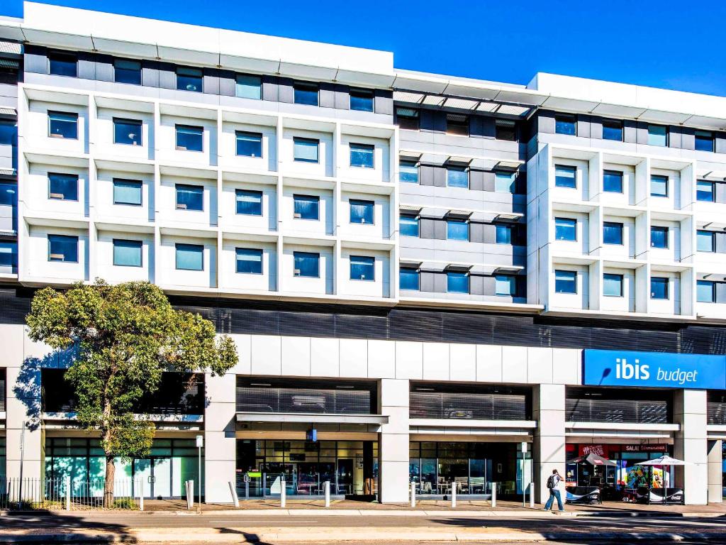 悉尼宜必思快捷酒店 - 悉尼奥林匹克公园的一座白色的大建筑,上面有蓝色的标志