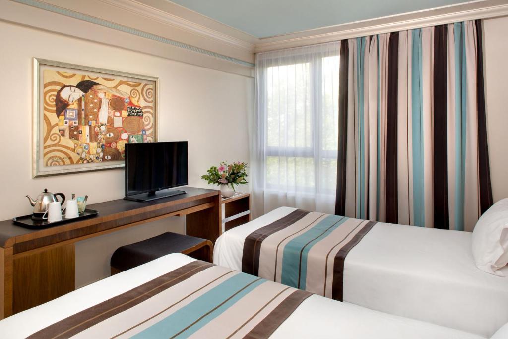 里尔欧洲里尔装饰艺术酒店的酒店客房设有两张床和一张书桌及电视