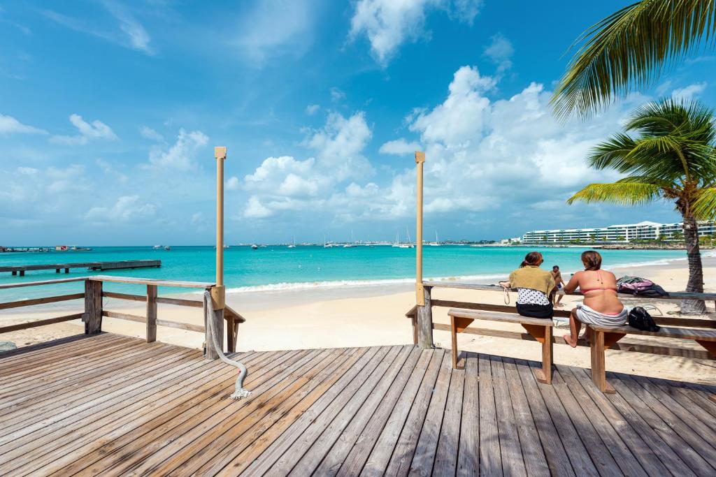 辛普森湾贝克套房酒店的两人坐在海滩上的长凳上
