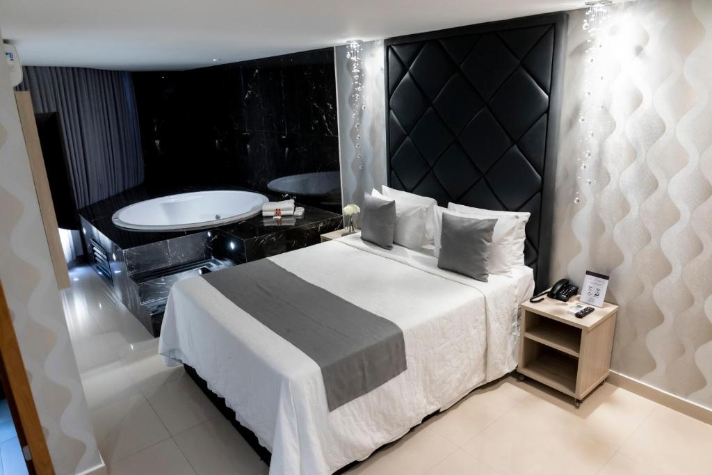 巴西利亚Cancún Hotel by H Hotéis - Airport的一间卧室设有一张大床和一个浴缸