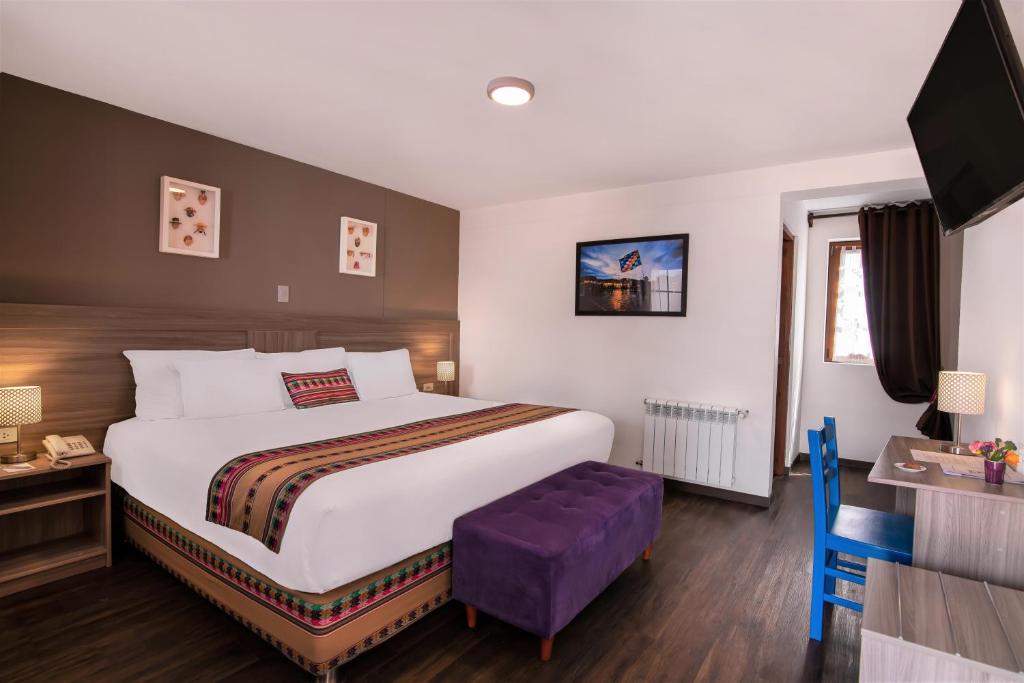 库斯科Atoq San Blas Hotel的酒店客房设有一张大床和紫色凳子