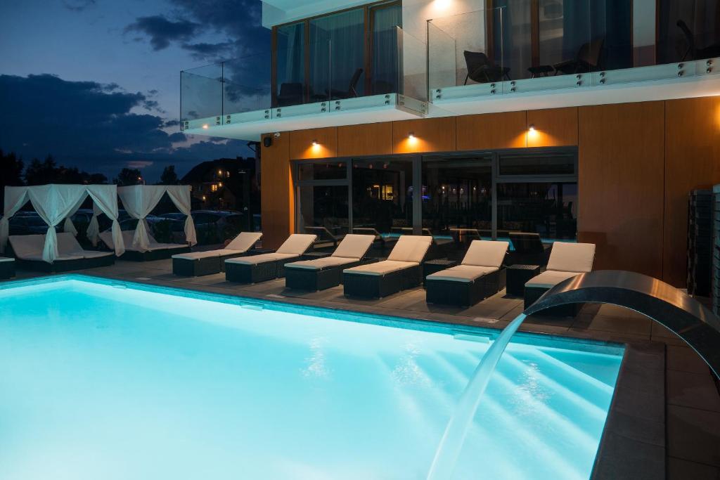 弗瓦迪斯瓦沃沃STELLA Resort & SPA的一座带躺椅的游泳池位于大楼旁
