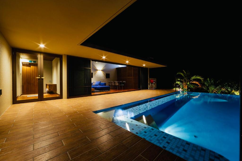 今归仁村relax kouri villa Rekrrr的夜间房子中间的一个游泳池
