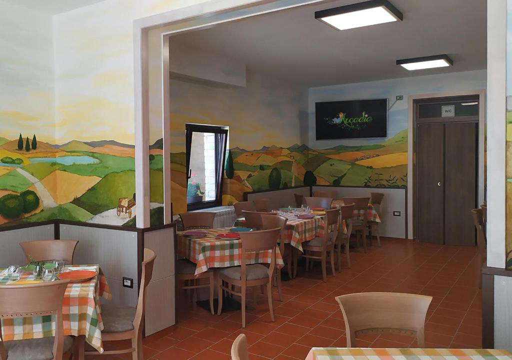 皮切尔诺Locanda Arcadia的餐厅设有桌椅,墙上挂有绘画作品