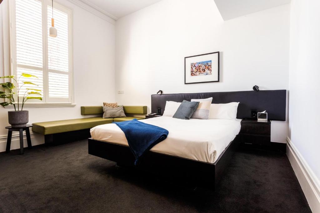 墨尔本米多百乐酒店的一间卧室配有一张大床和一张长凳