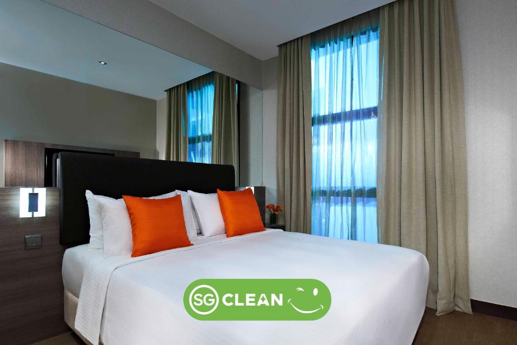 新加坡Aqueen Hotel Kitchener的一间卧室,床上有绿色的干净标志