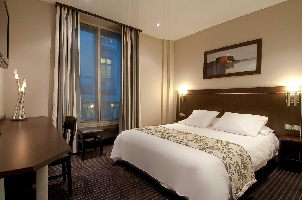 巴黎舒瓦瑟尔歌剧酒店的配有一张床、一张书桌和一扇窗户的酒店客房