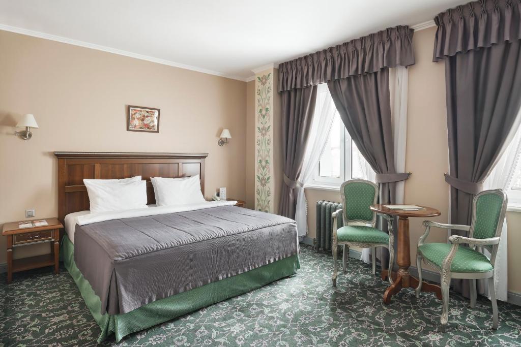 秋明列梅佐夫酒店的酒店客房,配有一张床和两把椅子