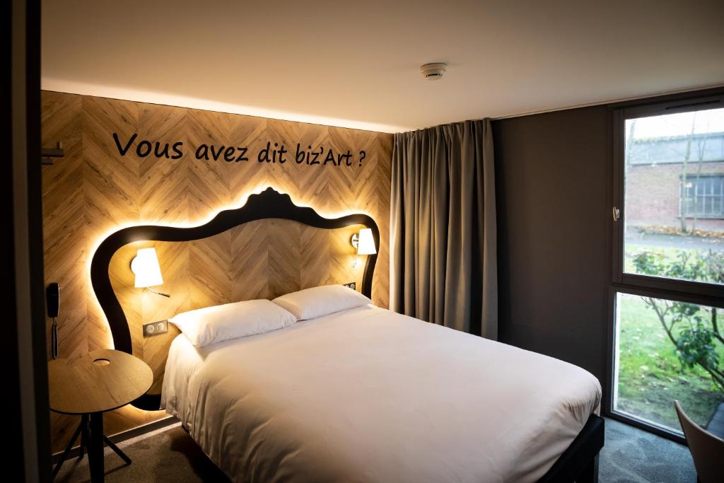 杜埃ibis Styles Douai Gare Gayant Expo的卧室配有一张挂有墙上标志的床