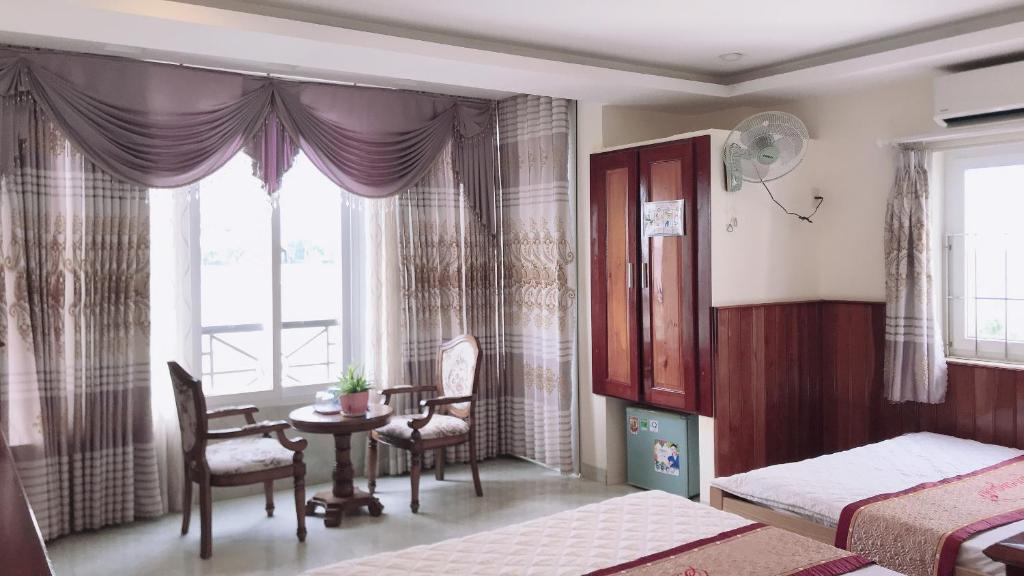 芽庄皇松酒店的一间卧室设有两张床、一张桌子和一个窗口