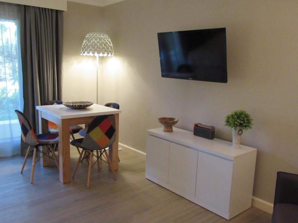 埃斯特角城Forest Lagoon Apartamento 6的客厅配有桌子和墙上的电视