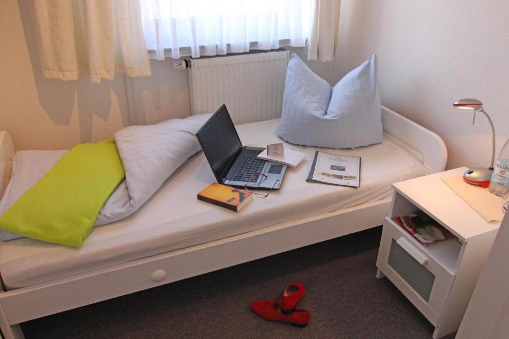 韦斯特兰Kapitaenshaus-Lassen-Zimmer-Kajuete的一张带笔记本电脑和枕头的床