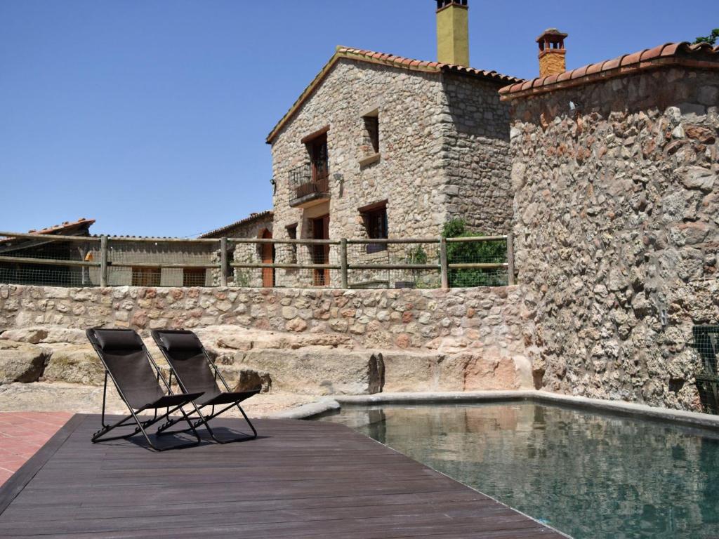 CastellolíBelvilla by OYO Cal Sant Miquel的游泳池旁的甲板上摆放着两把椅子
