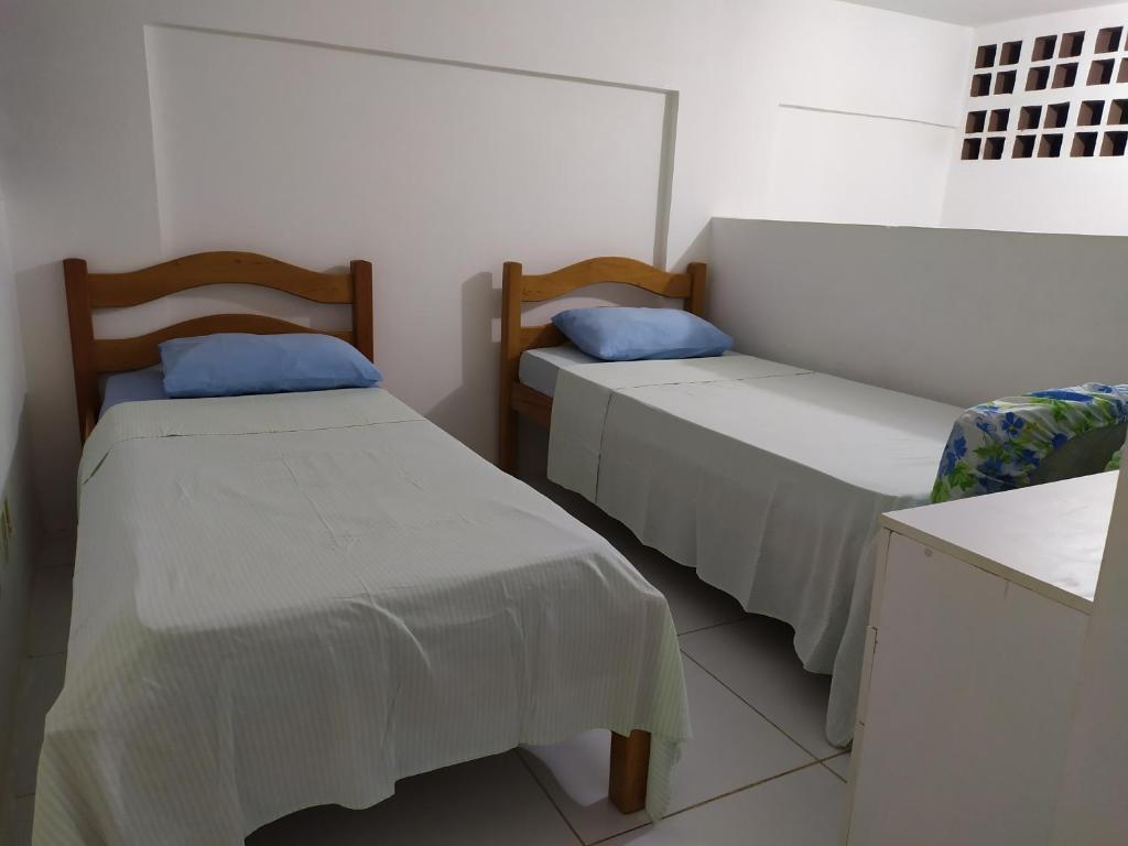 卡博迪圣阿戈斯蒂尼奥Reserva dos Corais的配有白色墙壁和蓝色枕头的客房内的两张床
