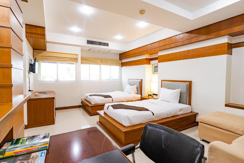 坤敬Sirin Hotel & Resident的一间卧室配有两张床、一张桌子和一把椅子