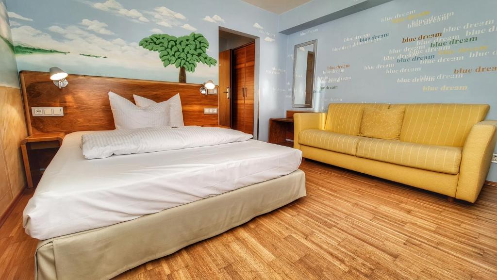 本斯海姆菲利克斯餐厅酒店的一间卧室配有一张床和一张黄色的沙发