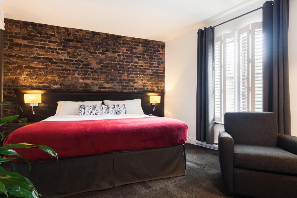魁北克市考特里尔酒店的卧室设有砖墙、一张床和一把椅子