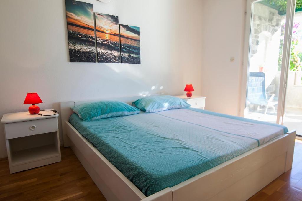 波尔Apartments Radić的一间卧室配有一张带蓝色枕头的床和两盏灯。