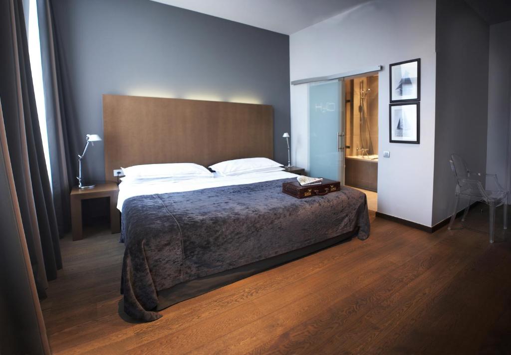 勃姆多莫斯酒店的一间卧室配有一张大床和木制床头板