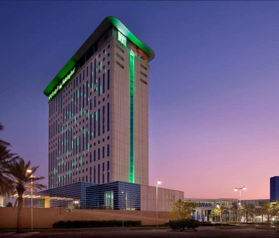 迪拜Holiday Inn & Suites - Dubai Festival City Mall, an IHG Hotel的一座高大的建筑,上面有绿灯