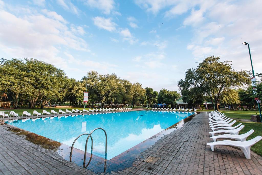 LetsiteleATKV Eiland Spa的一座带白色椅子和树木的大型游泳池