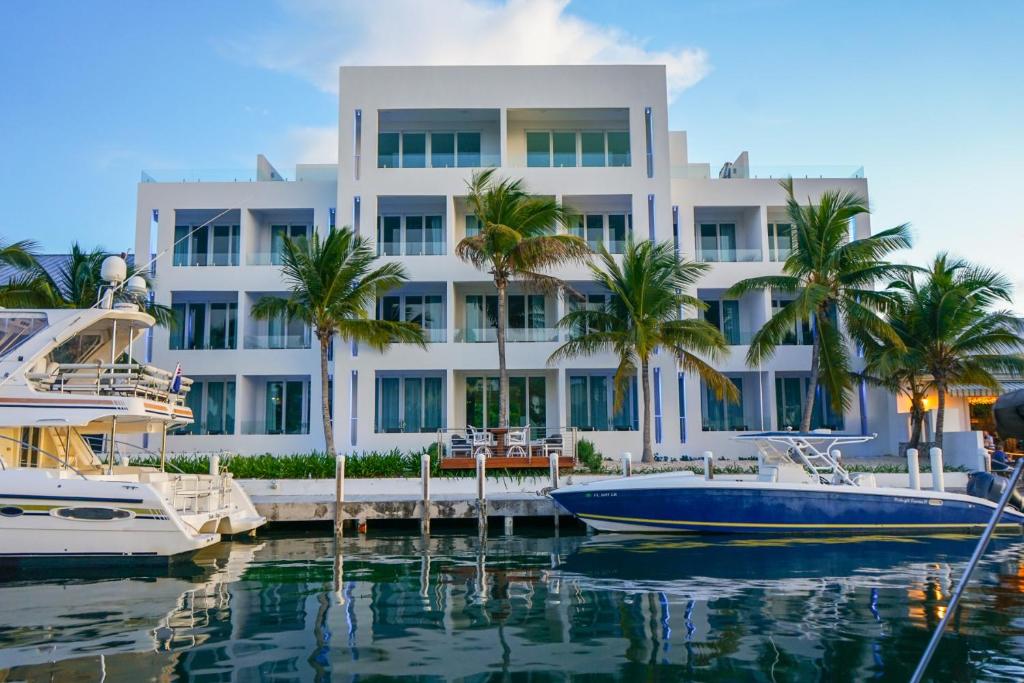 普罗维登西亚莱斯岛Zenza Boutique Hotel的一座白色的大建筑,棕榈树和水中的船只
