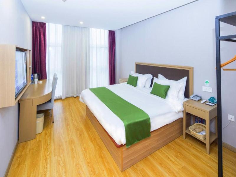 天津格林豪泰天津西青开发区人人乐广场智选酒店的一间卧室配有一张大床、一张桌子和一台电脑