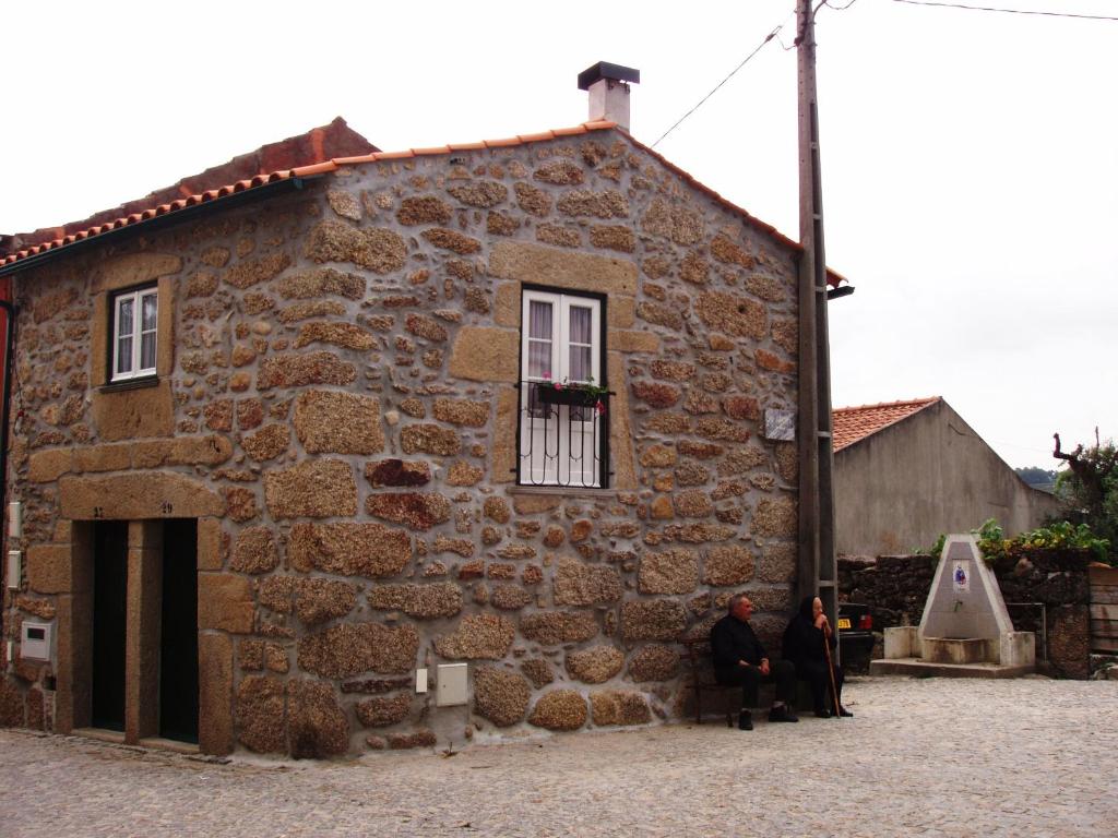 塞亚Casa d'avó Maria的两人坐在石头建筑外面