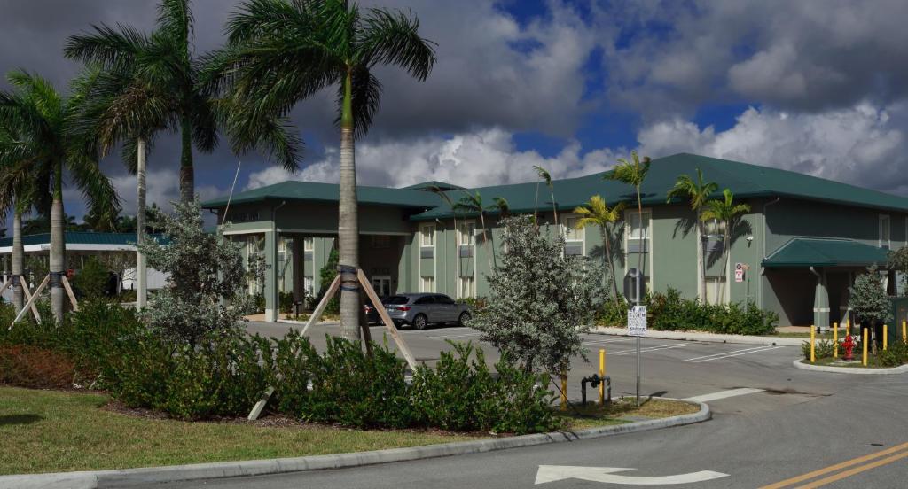 西棕榈滩Pioneer Inn的停车场前方的棕榈树建筑