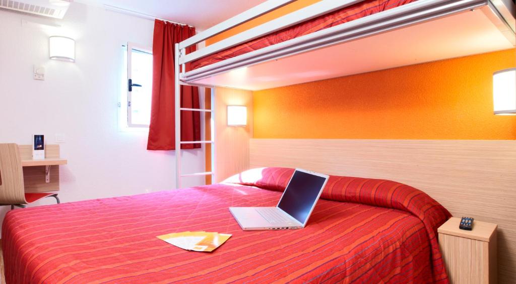 圣蒂博德维涅马恩河谷 - 圣蒂博德维涅普瑞米尔经典酒店的一间卧室配有一张带笔记本电脑的床