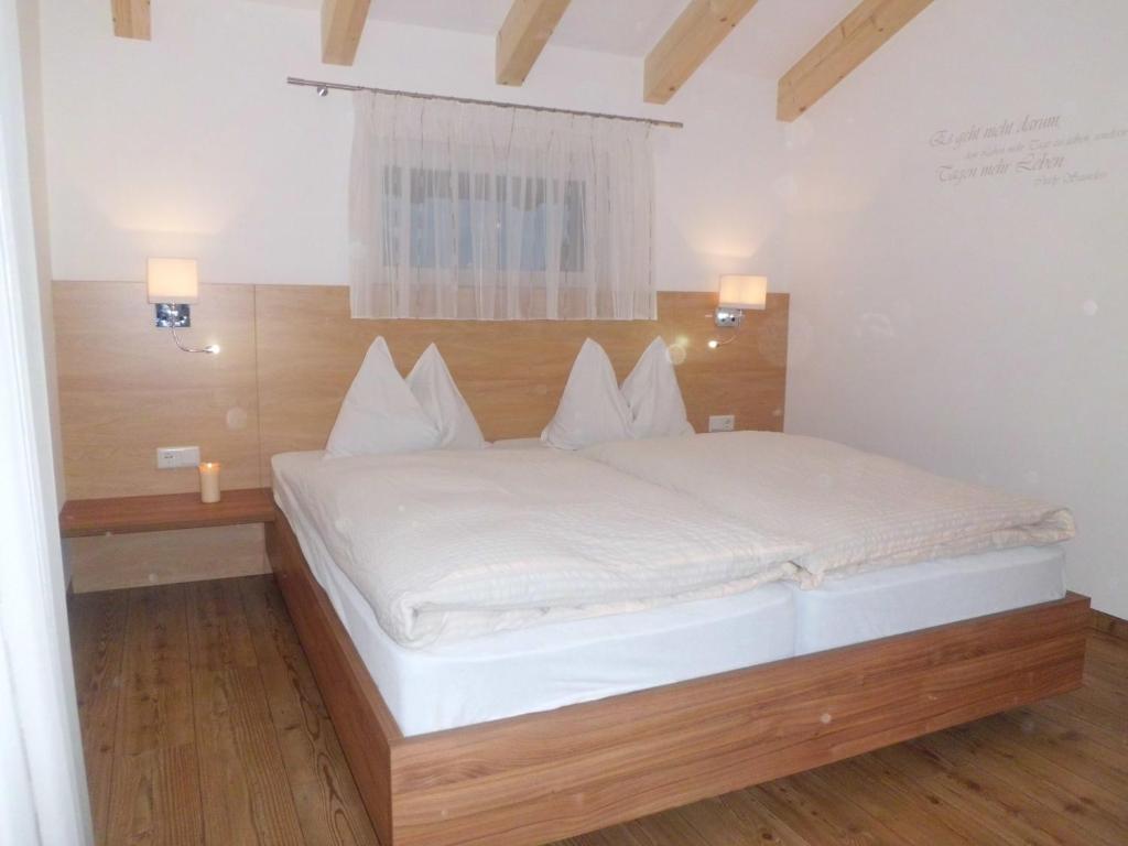 帕尔奇内斯Appartments Stoanegg的卧室配有白色的床和木制床头板