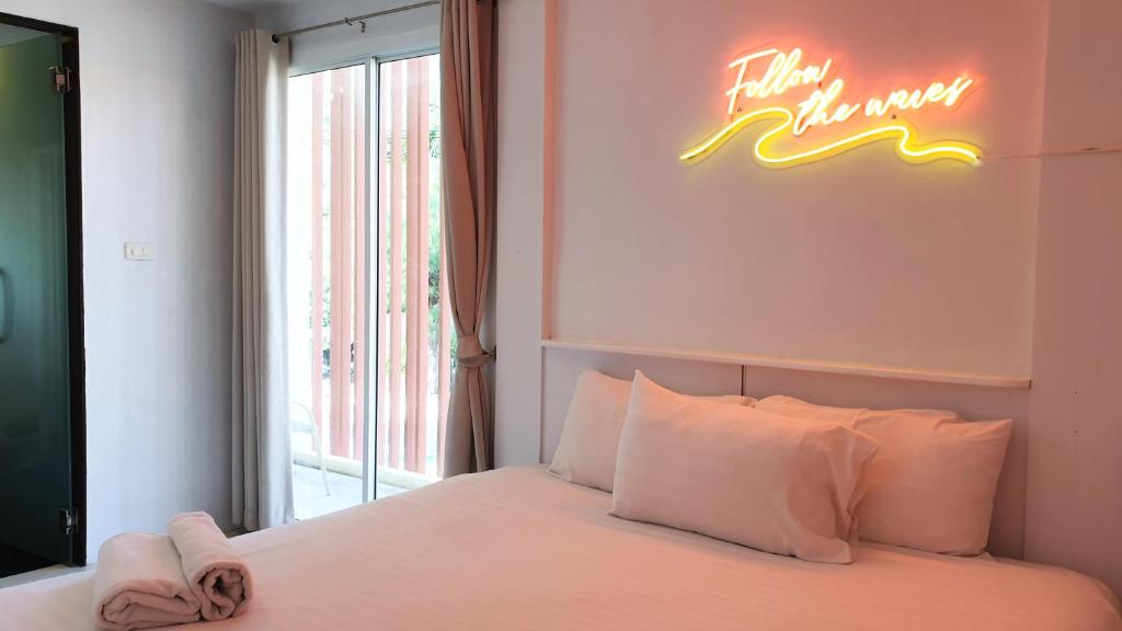 七岩七岩晚安迷你酒店的卧室配有一张墙上 ⁇ 虹灯标牌的床