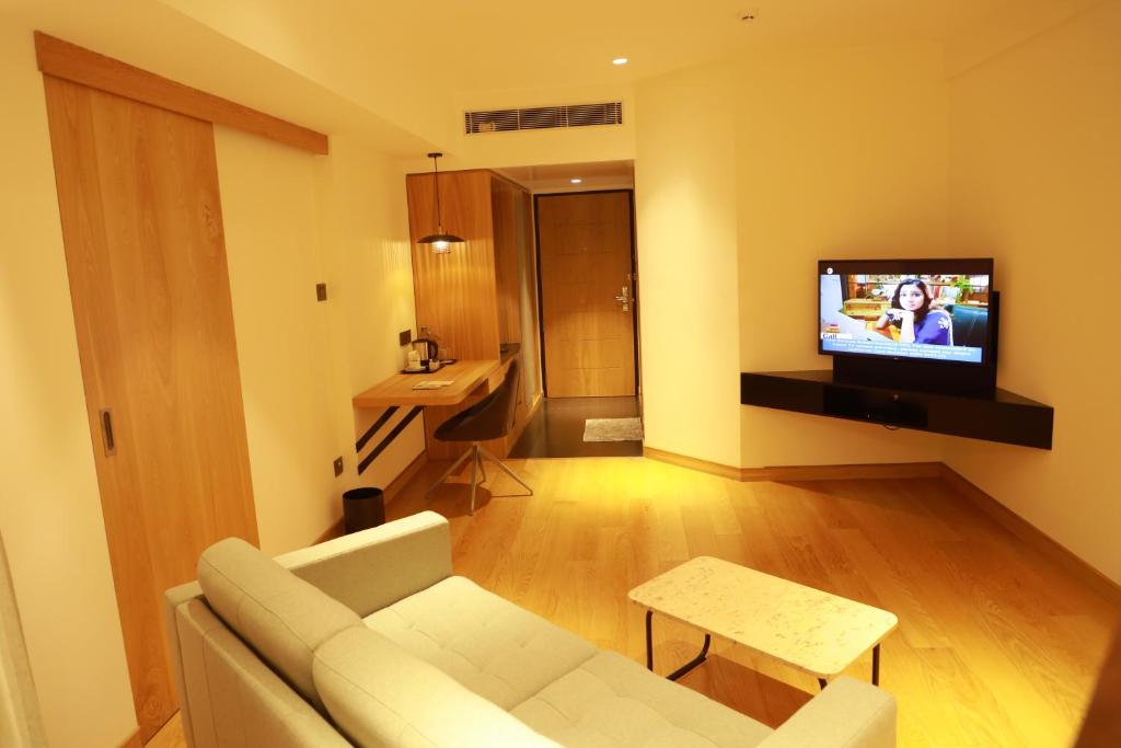 科泽科德Manuelsons Malabar Palace的客厅配有沙发和墙上的电视