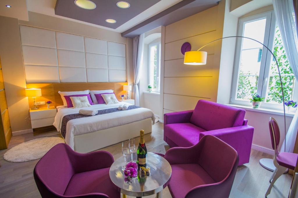 扎达尔半岛豪华旅馆的一间卧室配有一张床、紫色椅子和一张桌子