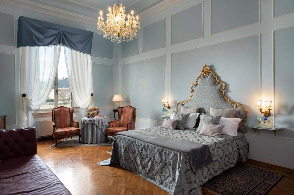 佛罗伦萨普林奇皮酒店的一间卧室配有一张床、一张桌子和一个吊灯。