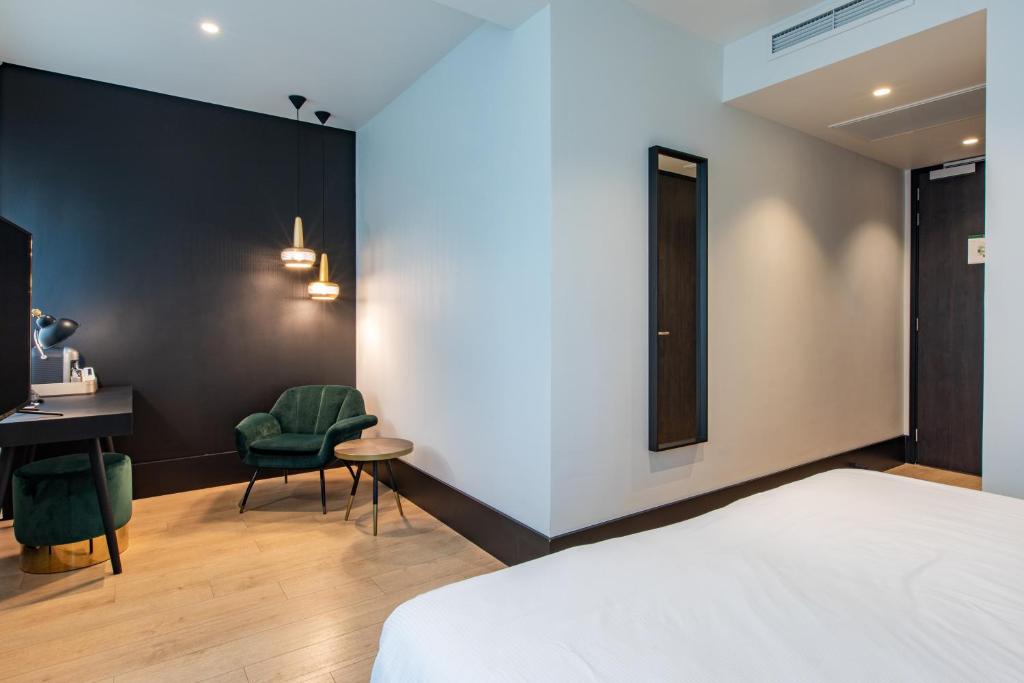 鹿特丹鹿特丹詹姆斯酒店的一间卧室配有一张床、一张桌子和一把椅子