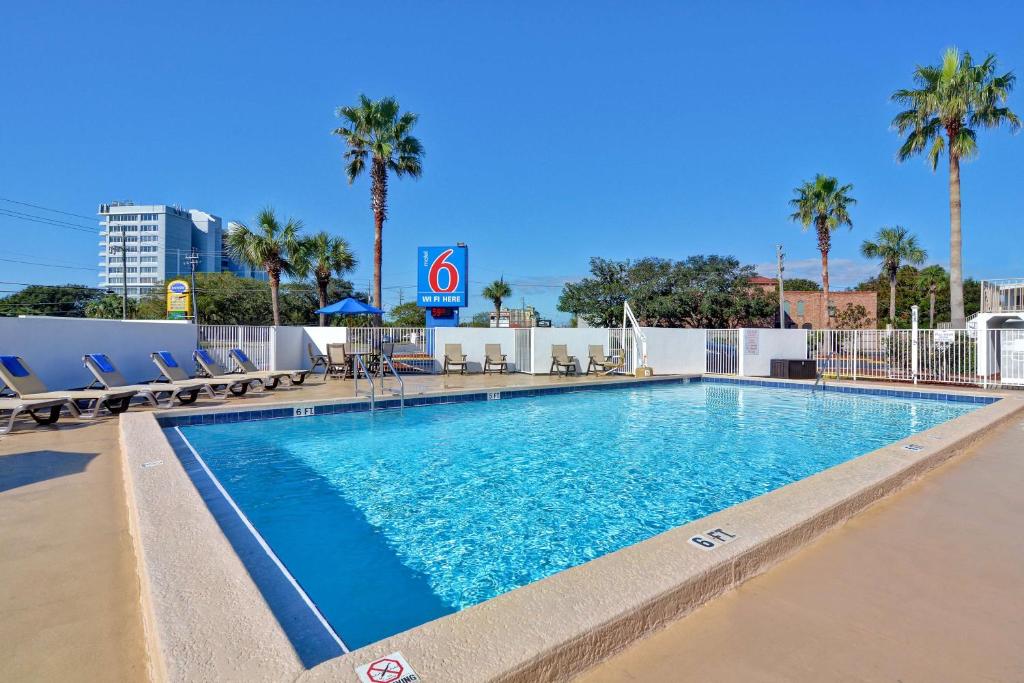 德斯坦德斯坦6汽车旅馆的一座游泳池,里面种有椅子和棕榈树
