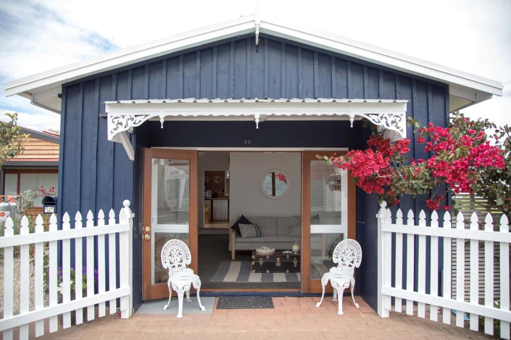 怀蒂昂格Beach Folly - Whitianga的蓝色的房子,配有两把椅子和围栏
